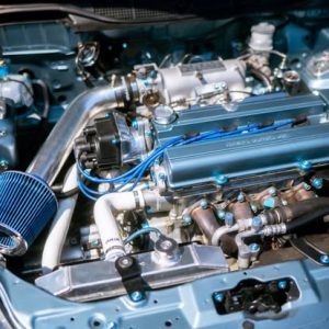 A high-performance car engine showcasing various components like the intake manifold, piping, and a blue air filter. The image highlights the intricate details of automotive engineering.