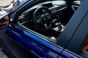The interior of a luxury car featuring a sleek dashboard, a modern steering wheel, and red leather seats. The image captures the high-end design and craftsmanship of the vehicle.