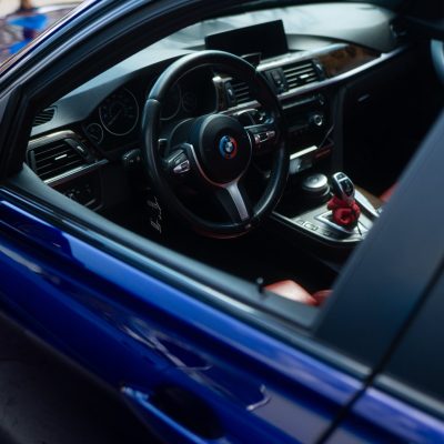 The interior of a luxury car featuring a sleek dashboard, a modern steering wheel, and red leather seats. The image captures the high-end design and craftsmanship of the vehicle.